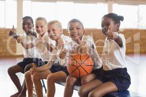 Smiling students with basketball showing thumbs up