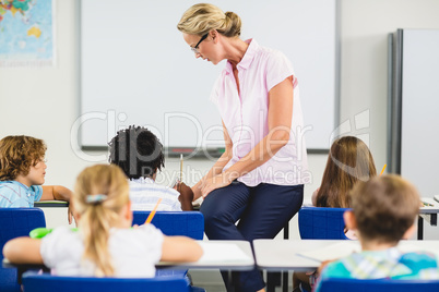 Teacher helping kids with their homework in classroom