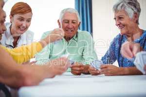 Smiling nurse and seniors people playing cards