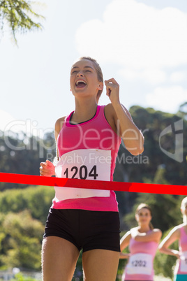 Cheerful winner athlete crossing finish line