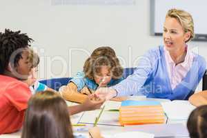 Teacher helping schoolgirl with her homework in classroom