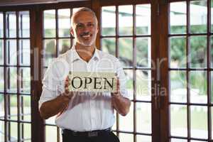 Smiling man holding a sign with open