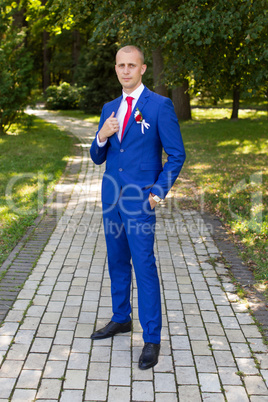 groom in a blue suit standing in the alley