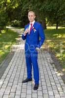groom in a blue suit standing in the alley