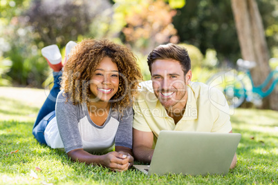 Portrait of couple smiling while using laptop