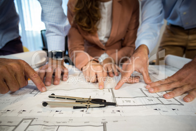 Businesswoman and coworker discussing blueprint on the desk