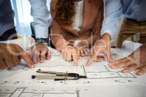 Businesswoman and coworker discussing blueprint on the desk
