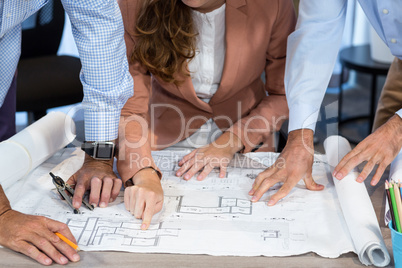 Businesswoman and coworker discussing blueprint on the desk