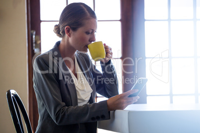 Woman drinking coffee and using smartphone