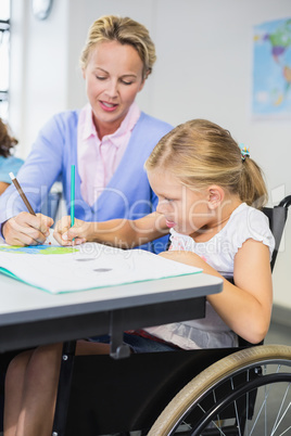 Teacher helping schoolgirl with her homework in classroom