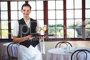 Smiling waitress holding a tray with glasses of wine