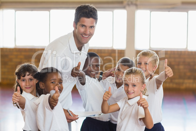 Portrait of sport teacher and students showing thumbs up