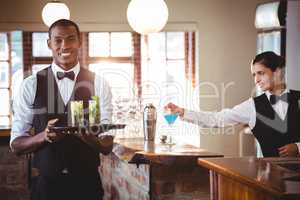 Bartender holding a serving tray with two cocktail glass