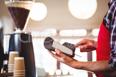 Mid section of waiter using credit card machine