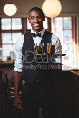 Bartender holding serving tray with glasses of beer