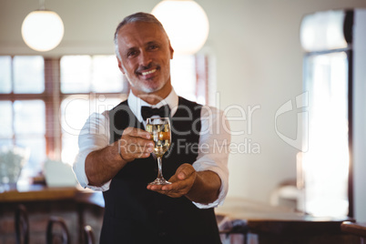 Smiling bartender offering a glass of wine at bar counter