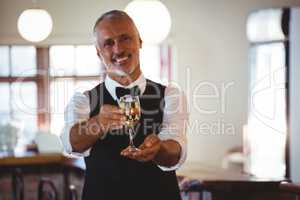 Smiling bartender offering a glass of wine at bar counter