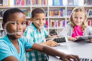 Kids using laptop and digital tablet in library