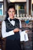 Portrait of bartender holding serving tray with glass of cocktai