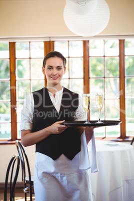 Portrait of waitress holding serving tray with champagne flutes&