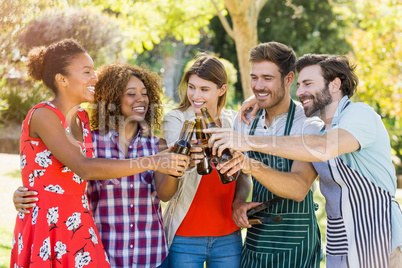 Group of friends toasting a beer bottle in park