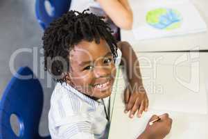 Portrait of schoolboy studying in classroom