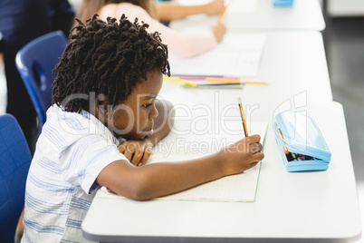 School boy doing homework in classroom