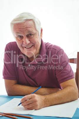 Portrait of  a smiling retired man writing on white paper