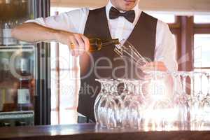 Mid section of bartender pouring a beer in a glass