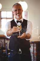 Smiling bartender offering a glass of wine at bar counter