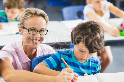 Teacher helping a boy with studies in classroom