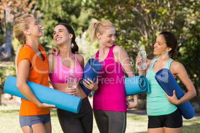 Beautiful women holding exercise-mat in park