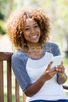 Portrait of woman using mobile phone while sitting on the bench