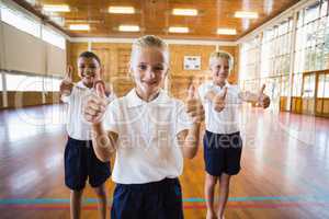 Smiling students showing thumbs up in school gym