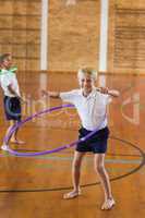 Schoolboy playing with hula hoop in school gym