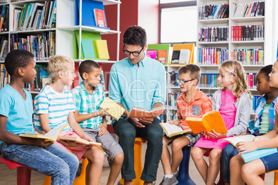 Teacher and kids reading book in library