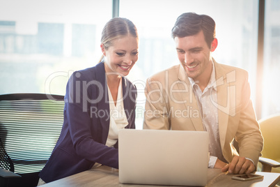 Businessman and businesswoman interacting using laptop