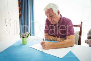 Portrait of retired man writing on white paper