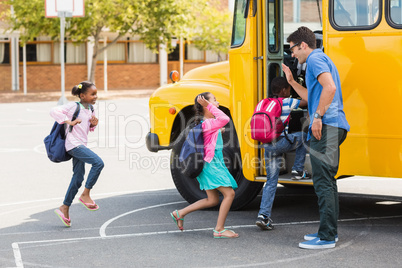 Teacher giving high five to kids while entering in bus