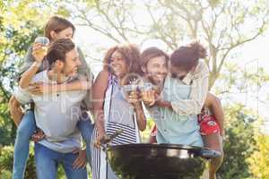 Men giving piggyback to women while preparing barbecue in park