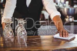 Mid section of bartender cleaning a bar counter