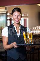 Portrait of waitress holding serving tray with two glass of beer