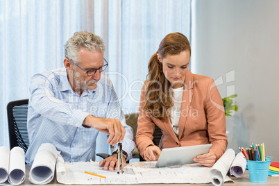 Businesswoman using digital tablet while coworker working on blu
