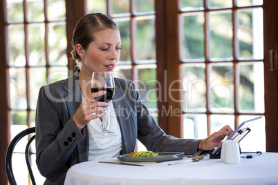 Woman using a tablet and drinking wine