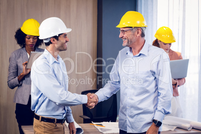 Two architects shaking hands in office
