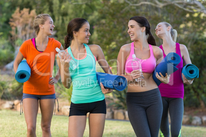 Beautiful women holding exercise-mat in park