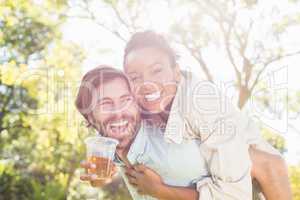 Man giving piggyback to woman while having glass of beer