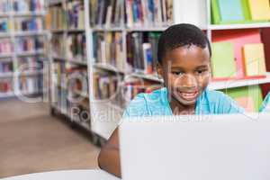 Schoolboy using laptop in library