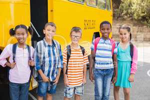 Smiling kids standing together in front of school bus