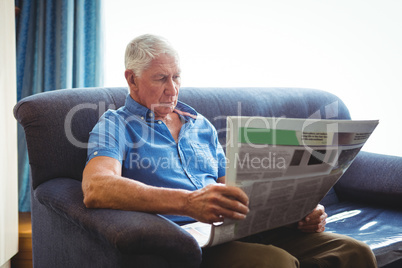 Senior man seated on a sofa reading